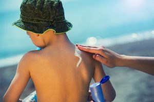 Parent putting sunscreen on boy