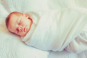 Swaddled infant in crib